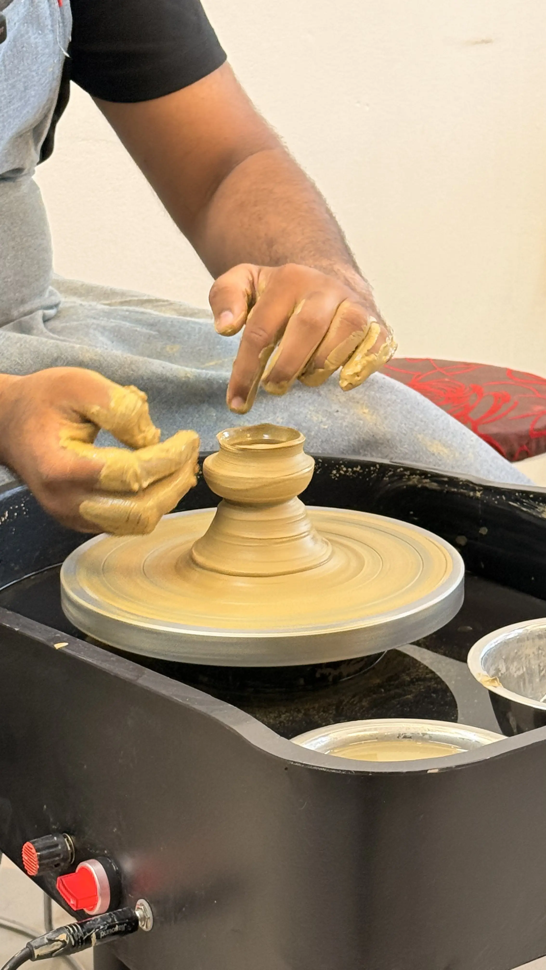 Hands shaping clay on a pottery wheel